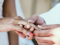 Billedet viser et close-up af to personers hænder, hvor den ene putter en ring på den andens finger