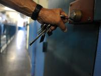Billedet viser et close-up af en fængselsbetjent, der er ved at låse en dør til en isolationscelle